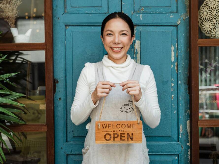 Woman holding a welcome we are open sign