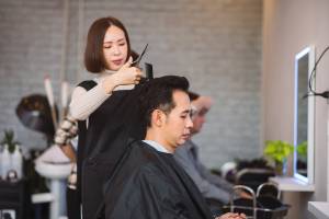 woman hairstylist and a man getting a haircut